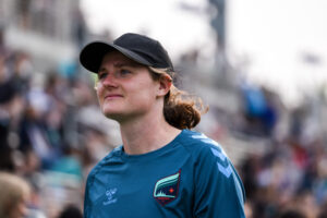 Coach Jen Larrick closeup with black baseball cap.